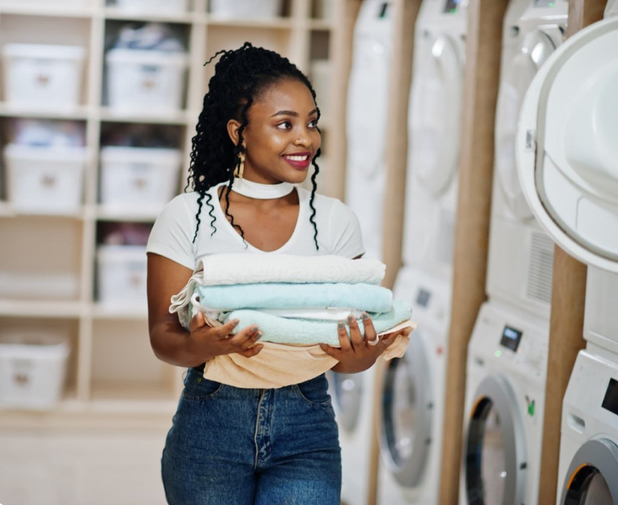 Smiling customer holding neatly folded laundry, ready for pickup and delivery